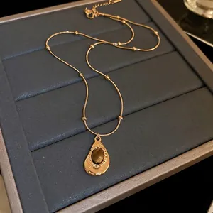 French vintage teardrop tiger eye pendant on a gold beaded chain necklace set on grey box