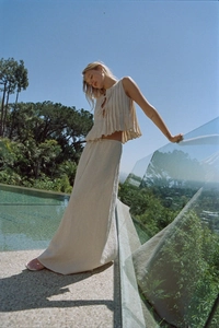 Close-up of beige pleated sleeveless top and maxi skirt set in breathable linen fabric