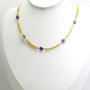 Close-up of gold chain necklace featuring five blue and white evil eye charms on a bust