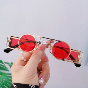 Steampunk punk sunglasses with golden hollow frame and round red lenses in hand