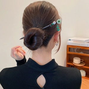 Détail d'une épingle à cheveux en bois vintage avec glands floraux sur un chignon élégant