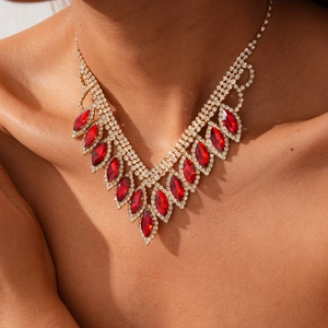 Macro detail of luxury gold V-shaped necklace with red marquise gems and white crystals