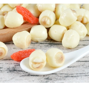 Detailed view of artificial lotus seeds and goji berries on a white ceramic spoon