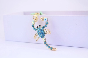 Dettaglio ravvicinato di un portachiavi a forma di scorpione con strass blu e metallo