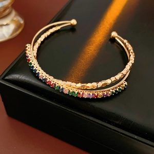 Macro detail of gold-plated double-layer cuff with rainbow zircons and geometric texture