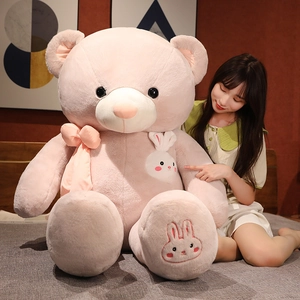 Detailed close-up of a large pink teddy bear plush with cute rabbit embroidery detail