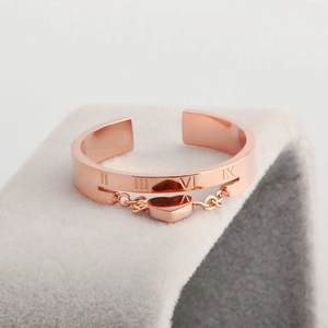 Rose gold open ring with Roman numeral engravings and a hanging heart charm