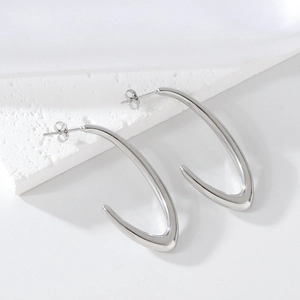 Detail of silver V-shaped stainless steel earrings on white textured stone and silk