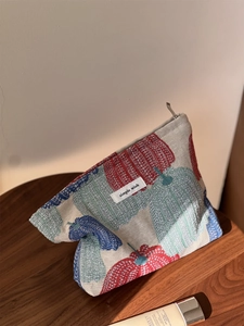 Close-up of woven pumpkin pepper pattern cosmetic bag with metal zipper and fabric label
