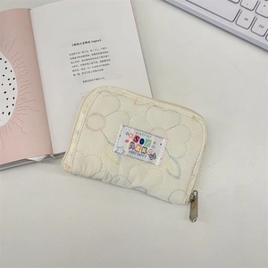Close-up of quilted cream wallet featuring colorful heart embroidery and secure zipper