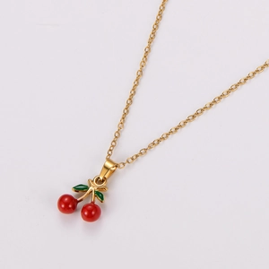 Detail of gold necklace with red cherry pendant and green leaves in enamel finish