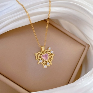 Macro shot of gold necklace with pink heart gemstone and sparkling spider web pendant