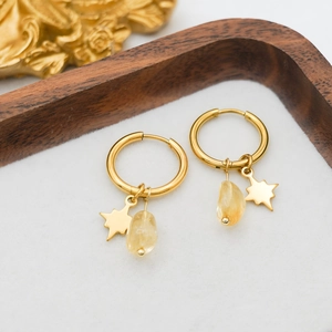 Close-up of gold-plated star charms and translucent natural stone drops on wooden tray