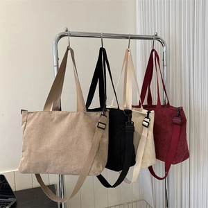Minimalist corduroy tote bags in four solid colors hanging on a modern metal display rack