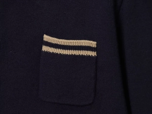 Close-up of navy knit polo shirt pocket with beige double stripe detail and fabric texture