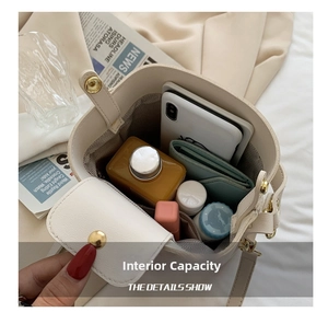 Spacious interior of beige bucket bag showing smartphone, wallet and drink bottle