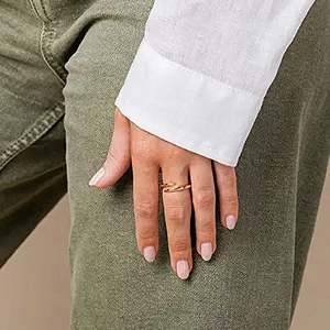 Detail of twisted gold ring on hand with elegant cross water drop design for women