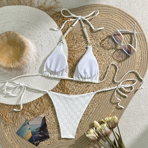 Detail of white checkered bikini with pearl straps and textured fabric flat lay