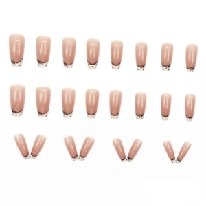 Lace style nude pink press-on nails with black dots and bow designs in long trapezoid shape