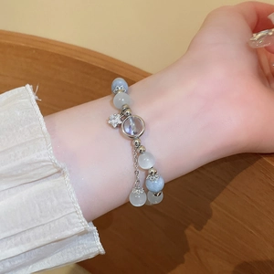 Detailed shot of star charm and cat's eye bead bracelet on a person's wrist