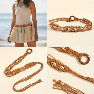 Detail of woven brown belt with white shells and a wooden buckle in bohemian style