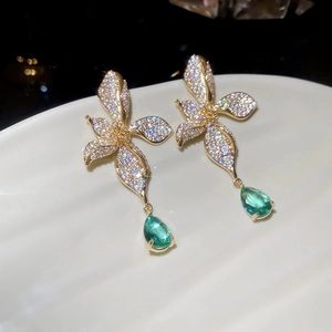 Macro detail of 18k gold plated flower earrings with pavé zircons and green teardrops