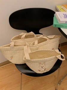 Quilted beige canvas organizers with cute rabbit and floral embroidery on a black chair