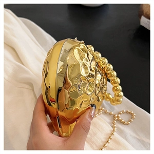 Dettaglio di una borsa da sera a cuore in oro metallizzato con manico a sfere e catena
