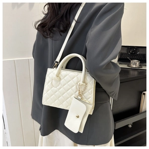 Detailed view of white quilted shoulder bag with detachable mini purse and crossbody strap