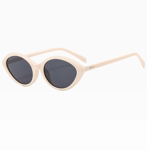 Detail view of cream cat-eye sunglasses with oval frames and silver metal dot accents