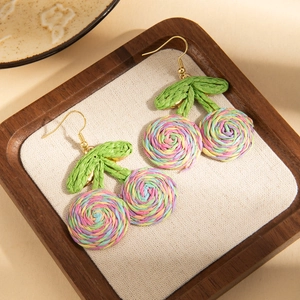 Macro shot of colorful woven cherry earrings with green leaves and gold metal hooks