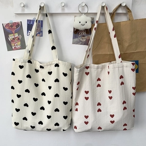 Detail of canvas tote bags with black and red heart patterns hanging on wall hooks