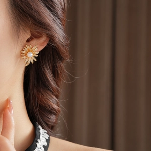 Close-up of pearl sunflower earring with white zircons on vintage golden petal studs