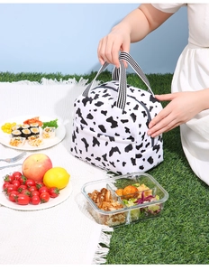 Sac à déjeuner isotherme à motif de vache sur une couverture de pique-nique sur l'herbe