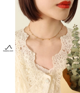 Close-up of minimalist golden stainless steel beaded chain necklace on a model
