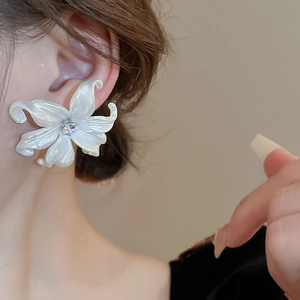 Elegant white acrylic flower earrings with crystal center on female model ear