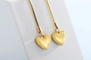 Macro shot of gold heart pendants on a sleek snake chain with minimalist lighting