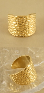 Detail view of the hammered texture and adjustable open structure of a golden wide ring