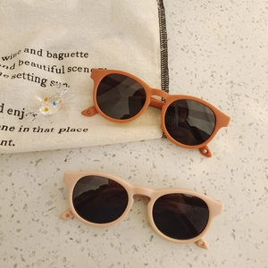 Detail view of round silicone sunglasses for babies in warm orange and beige tones