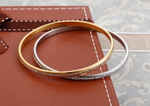 Dettaglio di bracciali sovrapposti in acciaio inox oro e argento con strass scintillanti