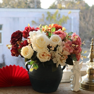 Detail of vintage silk rose bouquet in black ceramic vase with classical decor accents