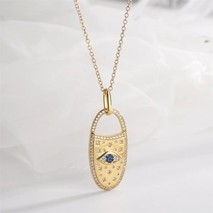 Detailed macro view of gold evil eye pendant with micro-pave crystals and blue stone