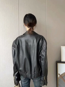 Détails de la veste de moto noire en similicuir avec ourlet élastique et zips