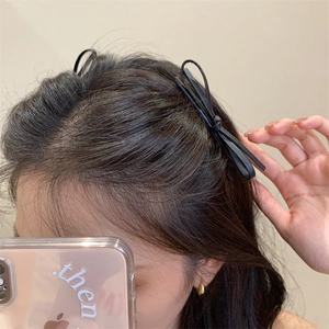 Detail shot of a black leather bow hair clip worn by a model for a trendy chic hairstyle