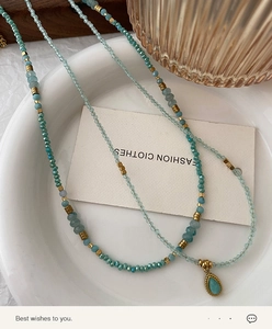 Detail of natural amazonite necklace with faceted blue beads and gold droplet pendant