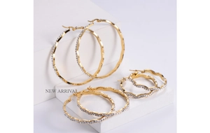 Detailed view of three sizes of gold wavy hoop earrings with micro-pave white crystals
