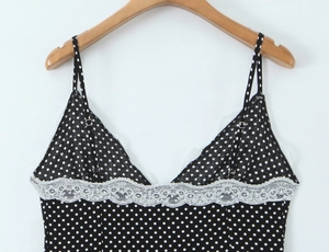 Detail of the white lace trim and black polka dot pattern on the V-neck camisole dress