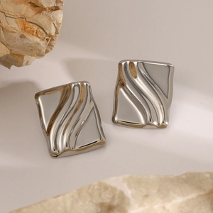 Macro shot of silver wave-textured rectangular earrings with decorative natural stones