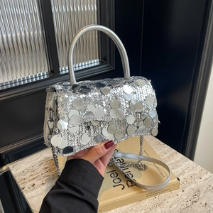 Close-up of silver sequin handbag with round glitter detail and metallic chain strap