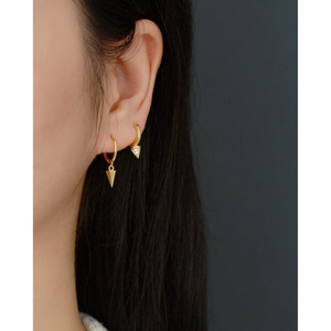 Detail of golden S925 silver hoop earrings with triangle and cone charm on model